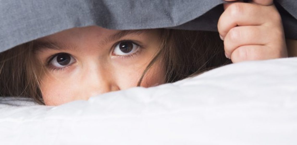 A Child or teen under covers in bed